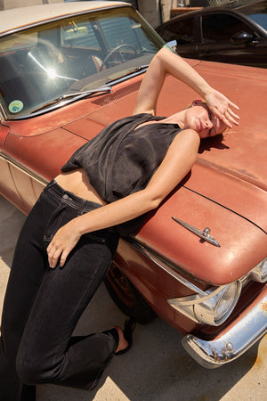 Woman wearing Du & Berry Twist Collared Top in Black leaning on vintage car hood