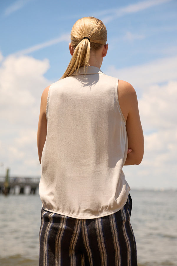 Back view of woman wearing Du & Berry Grey Twist Collared Top by the water on a sunny day