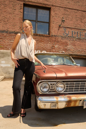 Woman wearing Du & Berry Grey Twist Collared Top paired with black pants standing next to vintage car