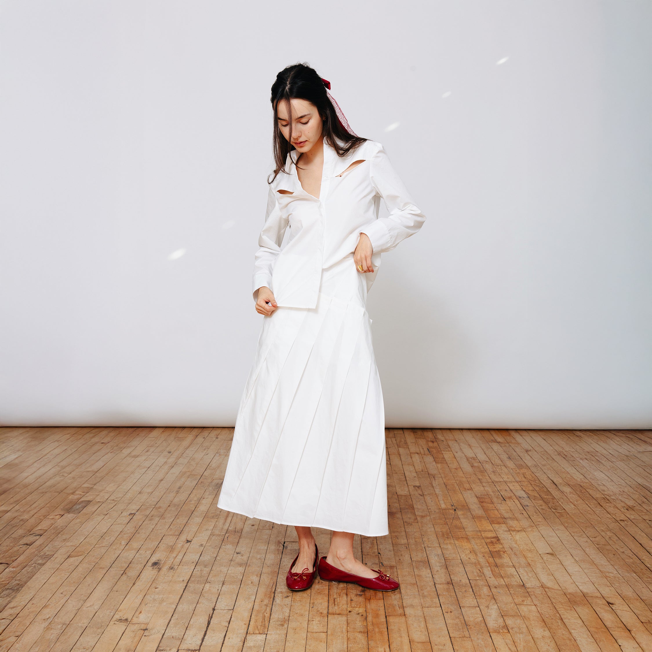 Model wearing Du & Berry Du Cotton Poplin Pleated White Skirt and Shirt with red flats and red bow