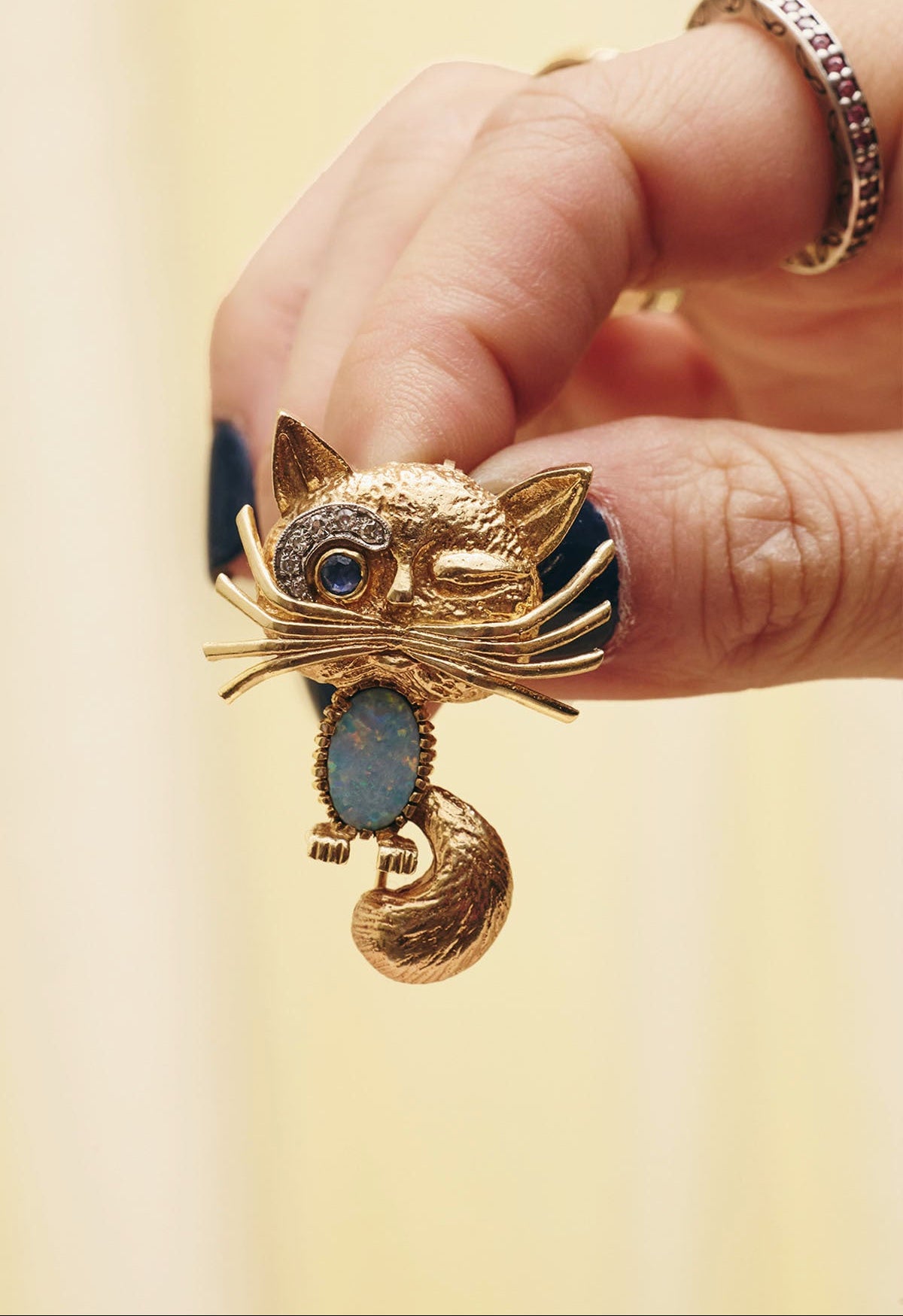 Du & Berry curated vintage - model holding 14K gold winking cat brooch/lapel pin with opal belly, diamond brow, and sapphire eye