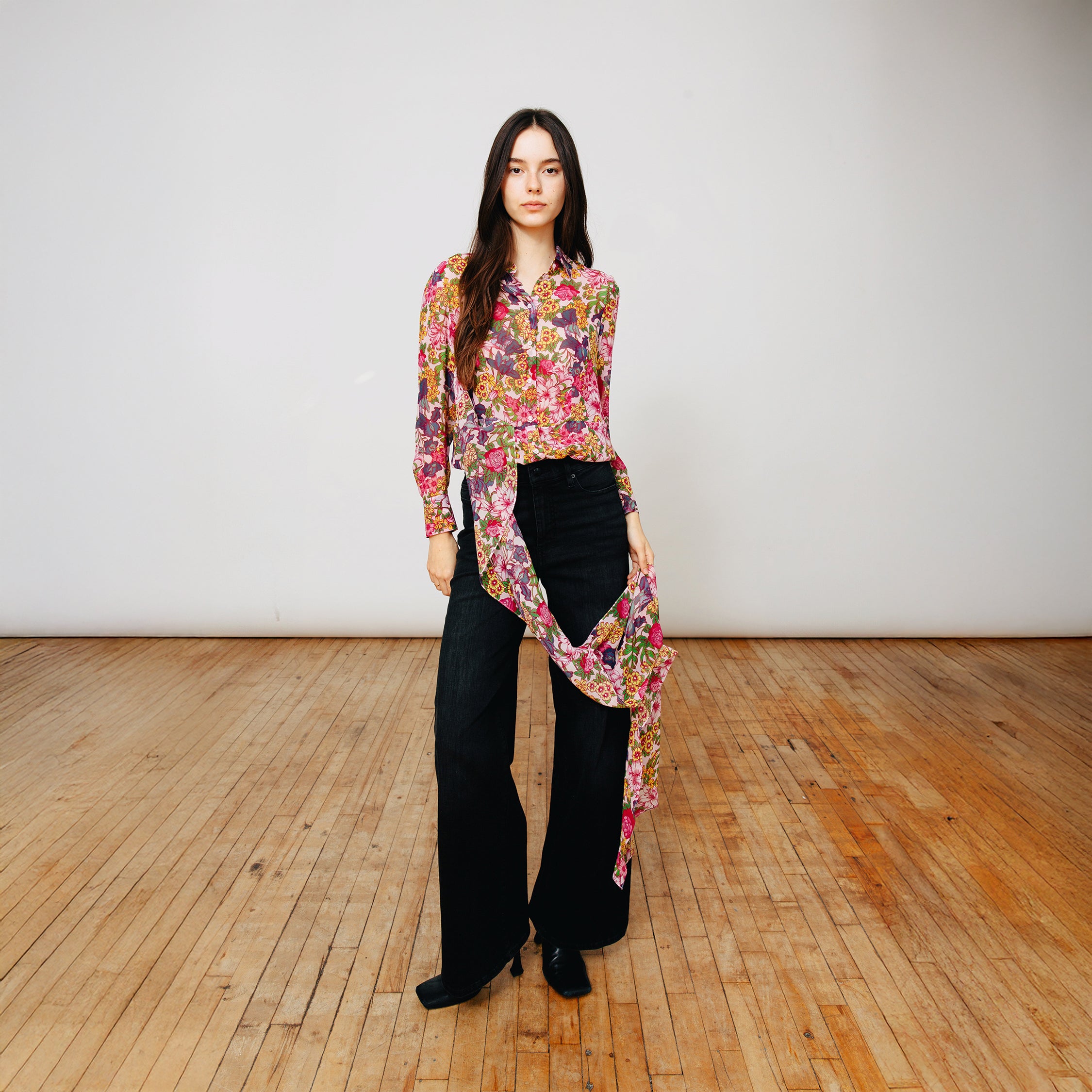 Model wearing Du & Berry Floral Symphony Silk Chiffon Scarf Blouse with black jeans and heeled booties.