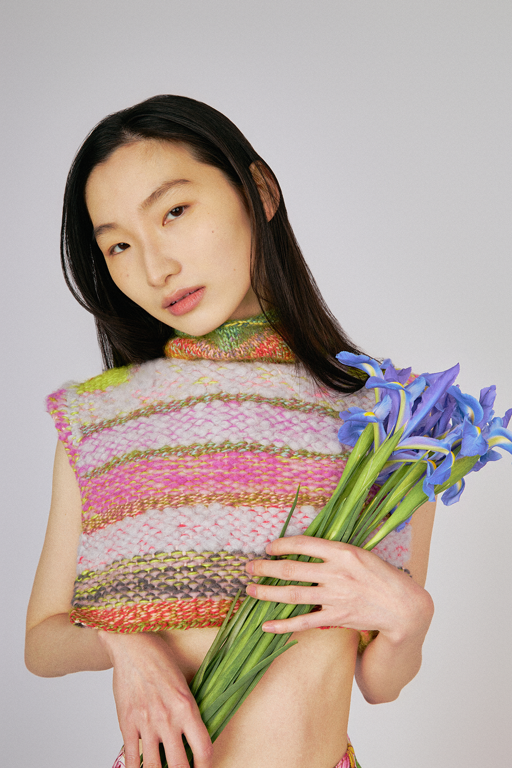 Up close view of model wearing Du & Berry one of a kind unique wool cashmere cropped turtleneck knit sweater top holding flowers