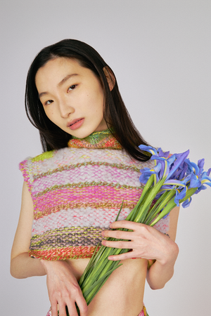 Up close view of model wearing Du & Berry one of a kind unique wool cashmere cropped turtleneck knit sweater top holding flowers