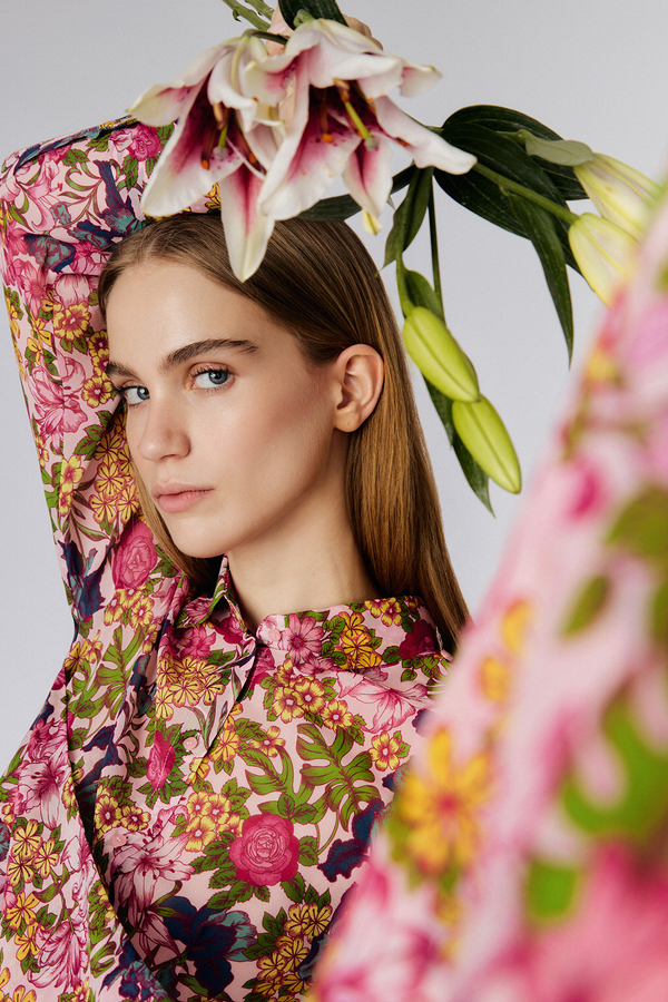 Up close shot of model holding flowers and wearing Du & Berry Floral Symphony Silk Chiffon Pink Button Up Blouse with scarf detail