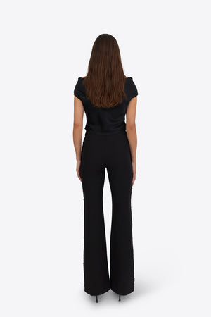 Woman wearing Du & Berry black flared pants and black top standing facing away