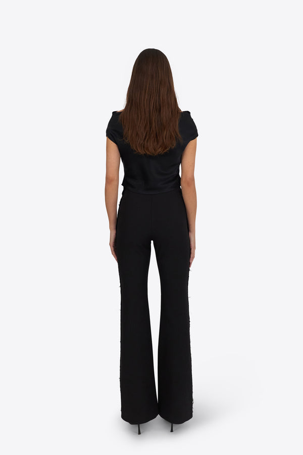 Woman wearing Du & Berry black flared pants and black top standing facing away