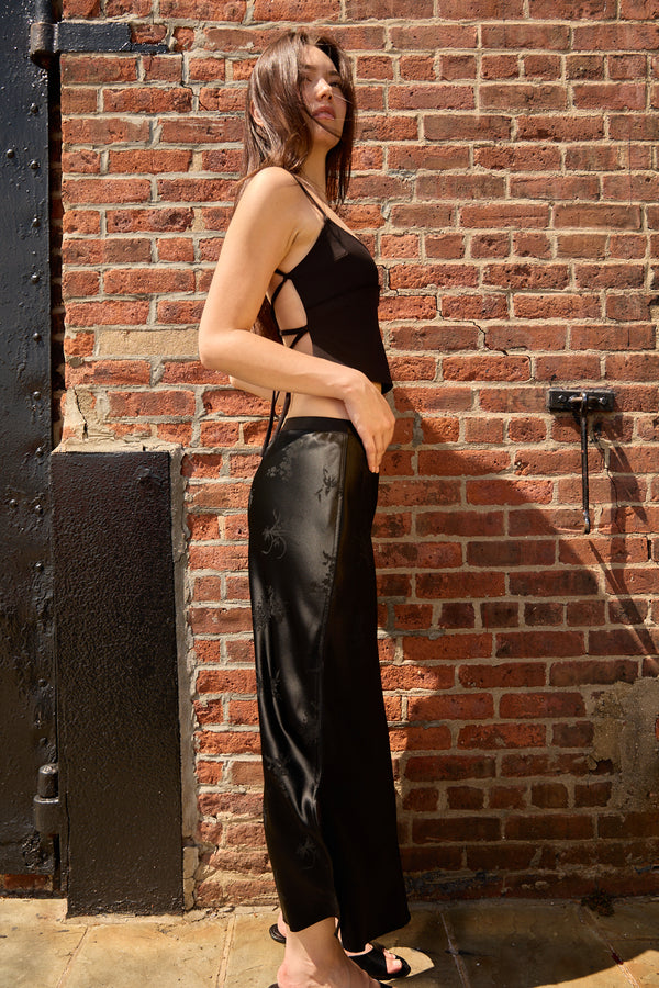 Du & Berry black jacquard midi skirt worn by model standing against a brick wall in stylish black top