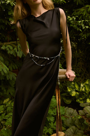 Du & Berry elegant black midi dress with sleeveless design and decorative waist chain in garden setting