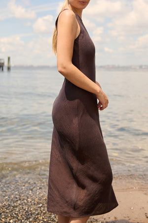 Du & Berry Brown Linen Side Split Maxi dress worn by model standing near water under blue sky