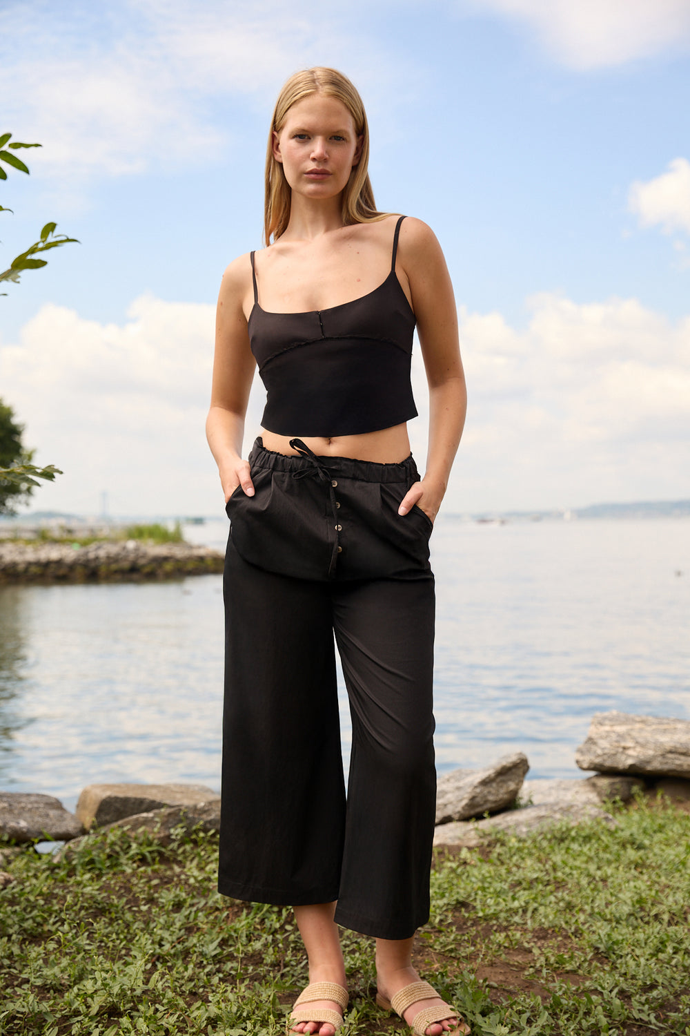 Du & Berry Cotton Palazzo Pants in Black worn by woman standing near water with a casual black top