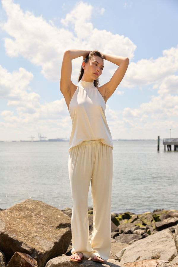 Woman wearing Du & Berry Cream Comfort Straight Pants standing on rocks by the water on a sunny day