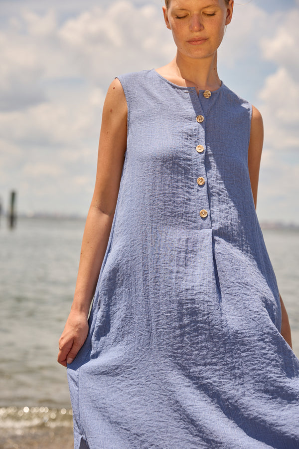 Du & Berry Blue Linen Button Midi Dress sleeveless with wooden buttons on light fabric by the water