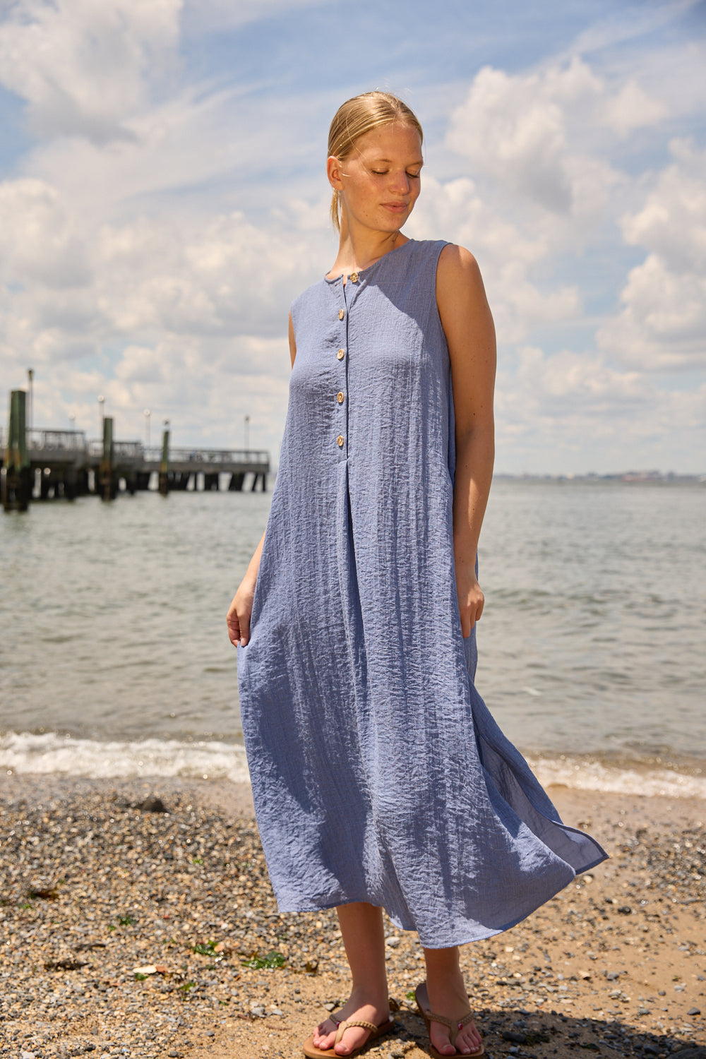 Du & Berry Blue Linen Button Midi Dress sleeveless flowy dress worn by a woman on the beach