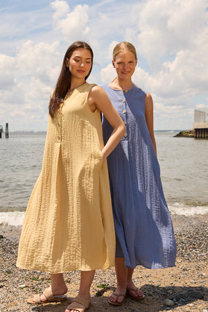 Du & Berry Blue Linen Button Midi Dress worn by a woman standing on a beach with another woman in a yellow dress