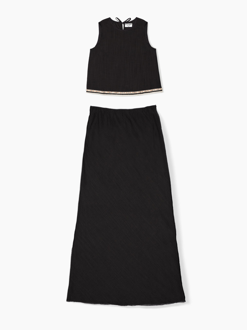 Du & Berry black linen top skirt set worn by model standing outdoors near water