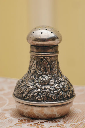 Du & Berry flower sterling silver shaker with detailed floral engravings on a lace tablecloth