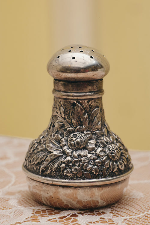 Du & Berry flower sterling silver shaker with detailed floral engravings on a lace tablecloth