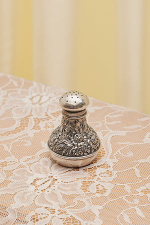 Du & Berry flower sterling silver shaker with intricate floral design on lace tablecloth