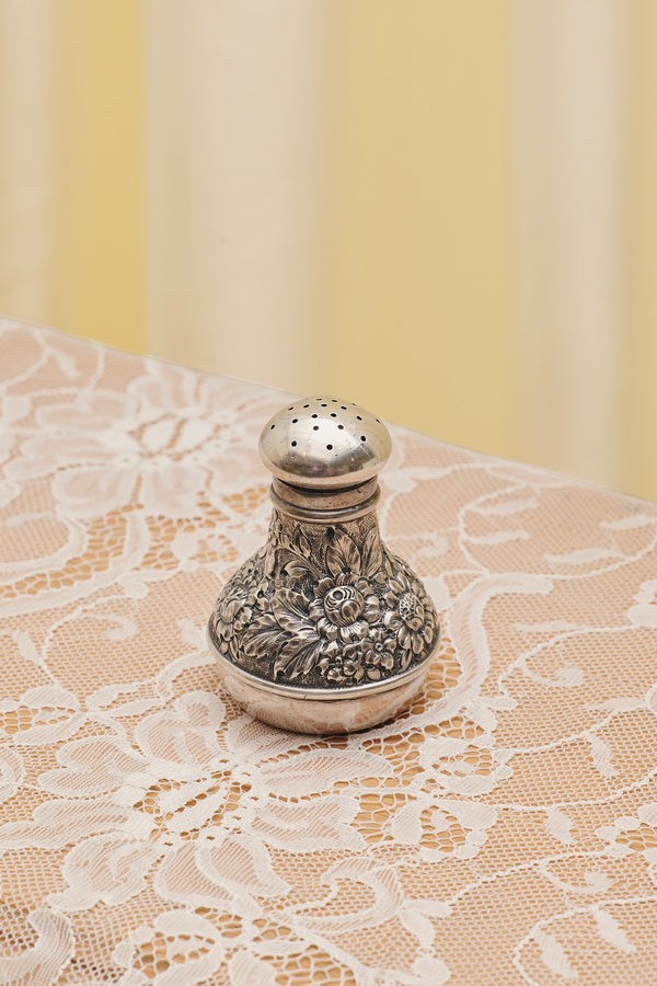 Du & Berry flower sterling silver shaker with intricate floral design on lace tablecloth