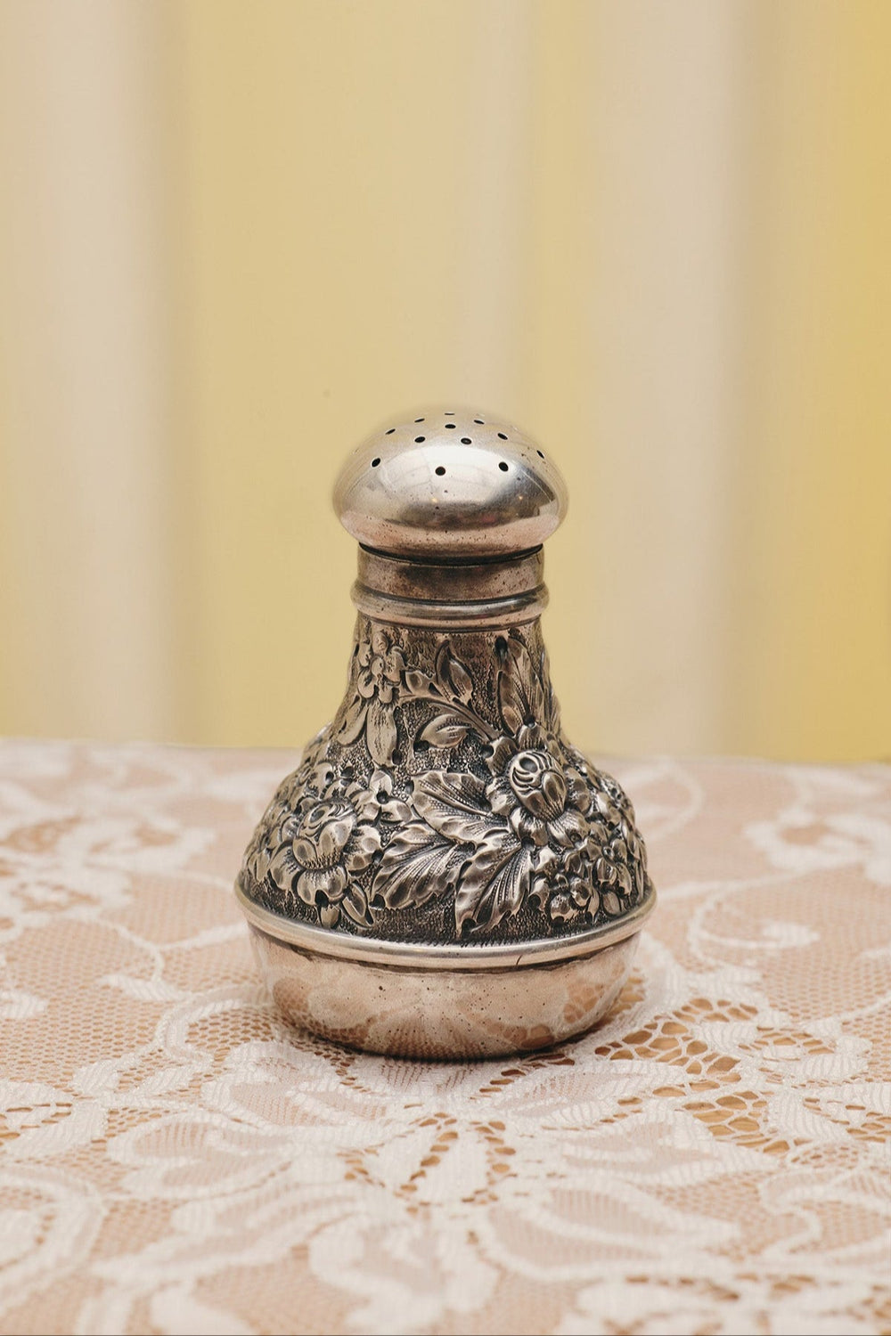 Du & Berry flower sterling silver shaker with intricate floral engravings on lace tablecloth