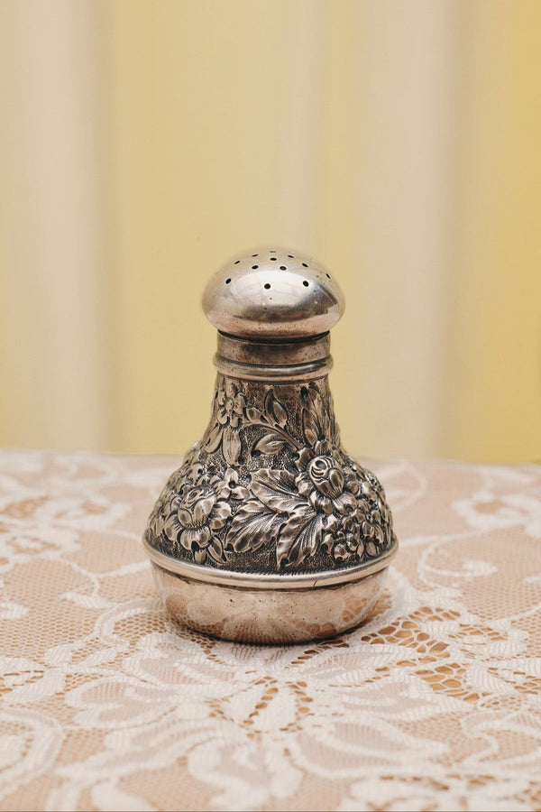 Du & Berry flower sterling silver shaker with intricate floral engravings on lace tablecloth