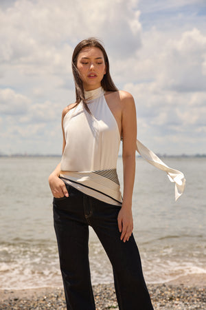 Woman wearing navy flare jeans for women from Du and Berry standing by the beach in a white sleeveless top