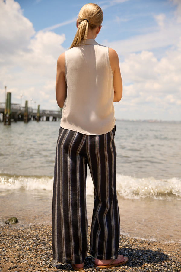 Woman wearing Du & Berry Navy Linen Wide Leg Stripe Pants standing on a beach with water and sky background