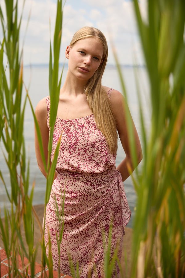 Du & Berry convertible silk wrap dress in pink floral pattern worn by woman outdoors near water