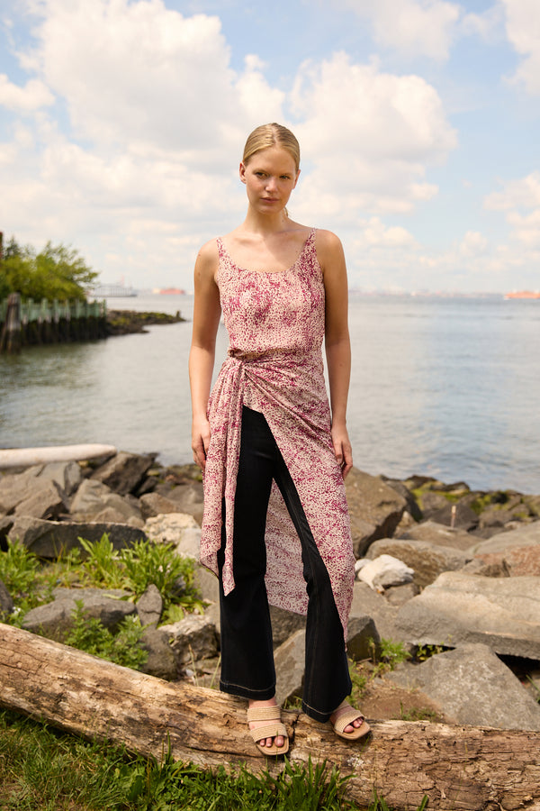 Du & Berry convertible silk wrap dress in pink floral print worn over black pants near rocky shoreline