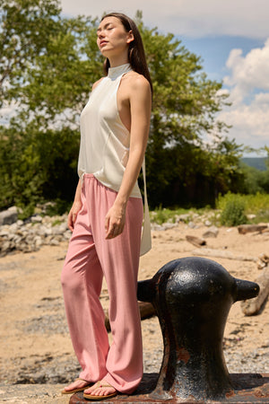 Woman wearing dusty rose straight pants from Du & Berry with a sleeveless white top outdoors