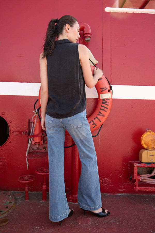 Woman wearing Light Blue Flared denim Jeans by Du & Berry standing against a red industrial background