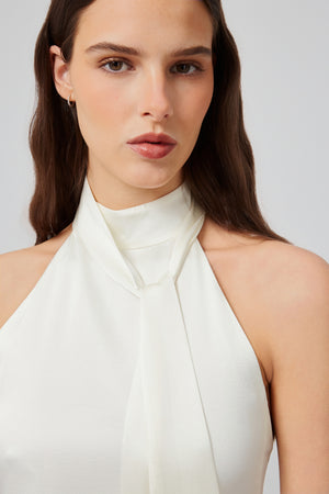 Close-up view of a white halter blouse by Du & Berry with a tied neckline detail