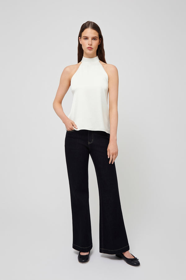 Front view: white halter blouse in lightweight fabric paired with black wide-leg jeans